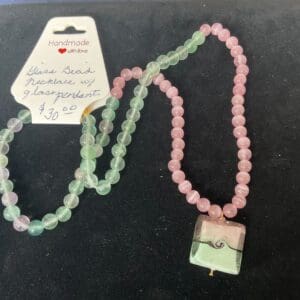 A necklace with pink and green beads on it.