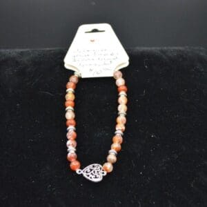 Orange gemstone bracelet with heart charm.